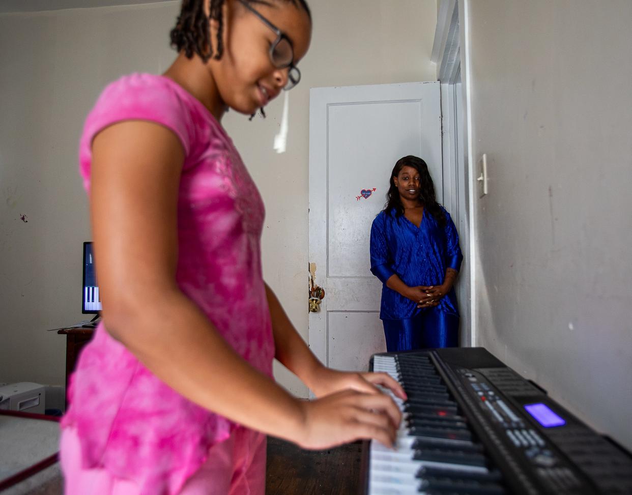 Kwmisha Adams, right, watches as her 10-year-old daughter Devaeh Snellen plays piano at their residence on Lindell Avenue in Louisville's Shawnee neighborhood. The house was built in the 1920s and has tested positive for lead paint in several areas in the home. Oct. 11, 2023