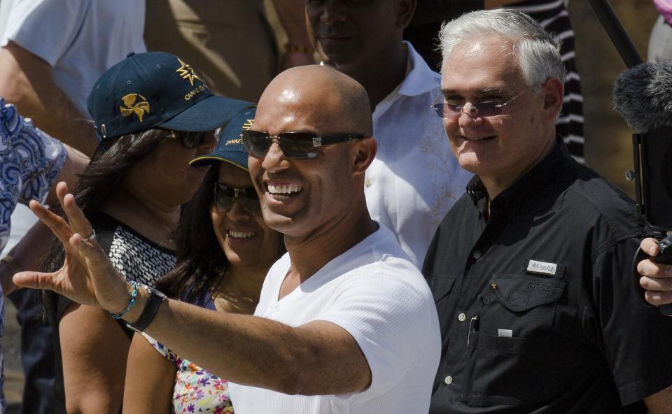 Mariano Rivera former New York Yankees baseball pitcher waves to the crowd, as Panama Canal Administrator Jorge Quijano, right, stands next to him during a visit to the Miraflores Locks at the Panama Canal in Panama City, Friday, March 14, 2014. The New York Yankees and the Miami Marlins will play on March 15-16, in the "Legend Series" to honor recently retired Yankees pitcher Mariano Rivera. (AP Photo/Tito Herrera)