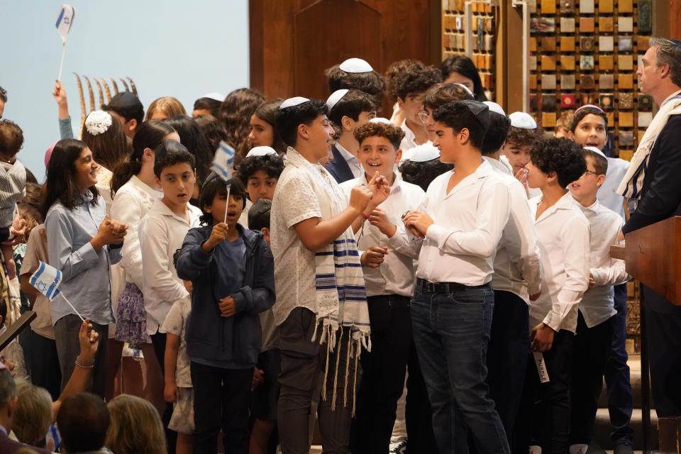 People sing the Israeli national anthem and wave Israel flags to conclude the service during Shabbat at The Sinai Temple in Los Angeles on Saturday, Oct. 14, 2023. The temple's worshippers, the majority of whom have family in Israel, were on edge after recent pro-Palestine rallies elsewhere in Los Angeles. The Shabbat service, themed "Sinai Temple Stands with Israel," featured prayers and songs for Israel, including the Israeli national anthem, to conclude the service as several people in the audience waved small Israeli flags. (AP Photo/Damian Dovarganes)