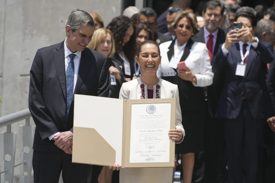 La presidenta electa de México, Claudia Sheinbaum, acompañada de su esposo Jesús María Tarriba, sostiene el documento oficial que la certifica como ganadora de las elecciones presidenciales al salir del Tribunal Federal Electoral, en la Ciudad de México, el jueves 15 de agosto de 2024. (AP Foto/Fernando Llano)