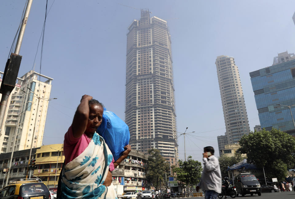 An Indian woman walks past an under construction building in Mumbai, India, Tuesday, Jan. 21, 2020. The IMF on Monday lowered India's economic growth estimate for the current fiscal to 4.8% and listed the country's Gross Domestic Product (GDP) numbers as the single biggest drag on its global growth forecast for two years. (AP Photo/Rafiq Maqbool)