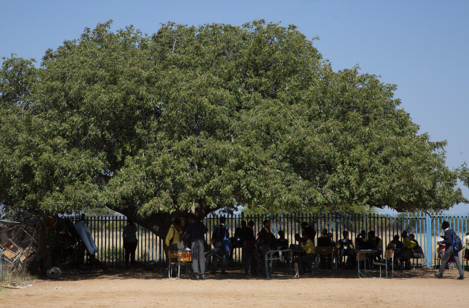 Students attend a class under a tree at the Seipone Secondary School in the rural village of Ga-Mashashane, near Polokwane, South Africa, Thursday May 4, 2023. Human rights groups have been pressuring the government for a decade to get rid of pit toilets in schools, with the issue given added urgency by several tragic cases of young children falling into the pits and drowning. (AP Photo/Denis Farrell)