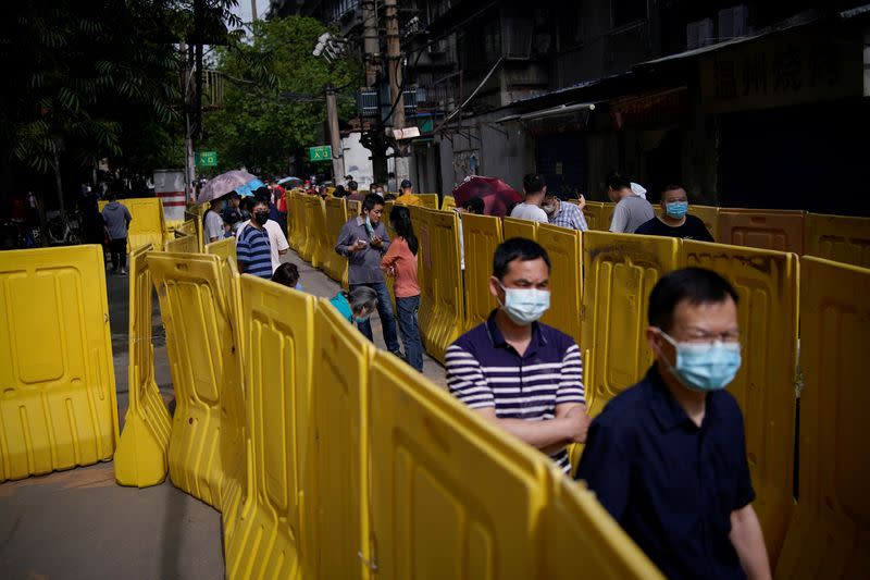 Residents wearing face masks line up for nucleic acid testings at a residential compound in Wuhan