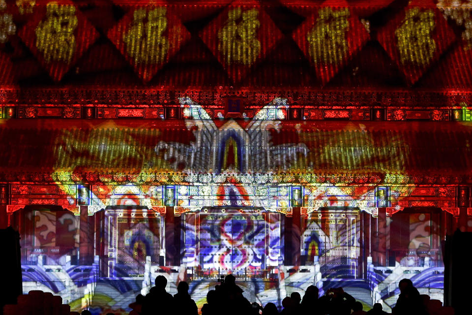 In this Tuesday, Feb. 19, 2019, file photo, visitors watch the Forbidden City is illuminated with colorful lights during the Lantern Festival in Beijing. Beijing's Palace Museum was illuminated and opened for night visits to celebrate China's Lantern Festival. For the first time since it was established 94 years ago, the Palace Museum, also known as the Forbidden City, extended opening hours till nighttime and lit up part of its cultural relics buildings. (AP Photo/Andy Wong, File)