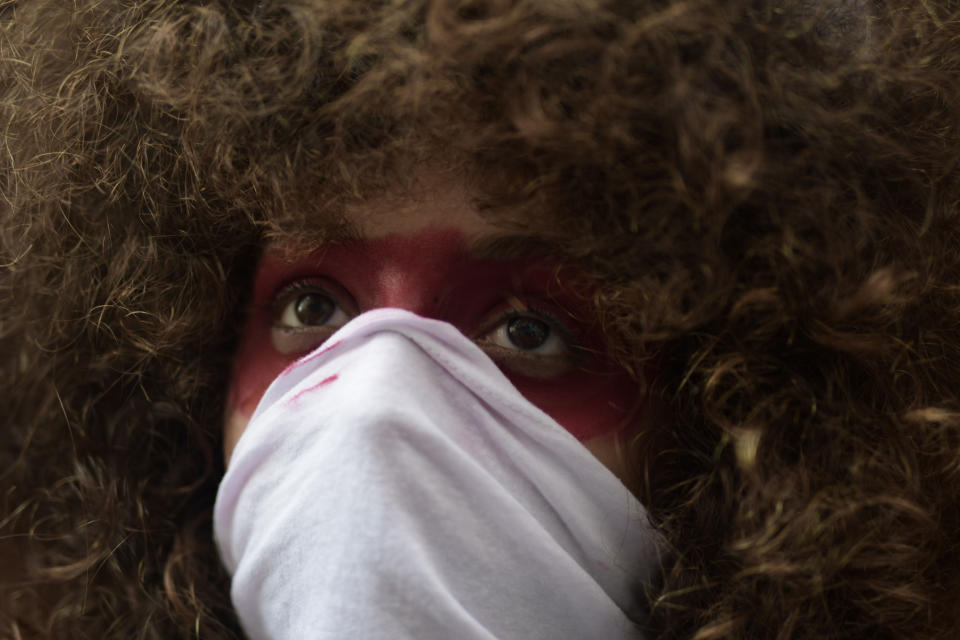 A young woman covers her face while protesting outside the executive mansion known as La Fortaleza, in Old San Juan, demanding the resignation of Governor Wanda Vazquez after the discovery of an old warehouse filled with unused emergency supplies in San Juan, Puerto Rico, Monday, Jan. 20, 2020. Anger erupted on Saturday after an online blogger posted a live video of the warehouse in the southern coastal city of Ponce filled with water bottles, cots, baby food and other basic supplies that had apparently been sitting there since Hurricane Maria battered the U.S. territory in September 2017. (AP Photo/Carlos Giusti)