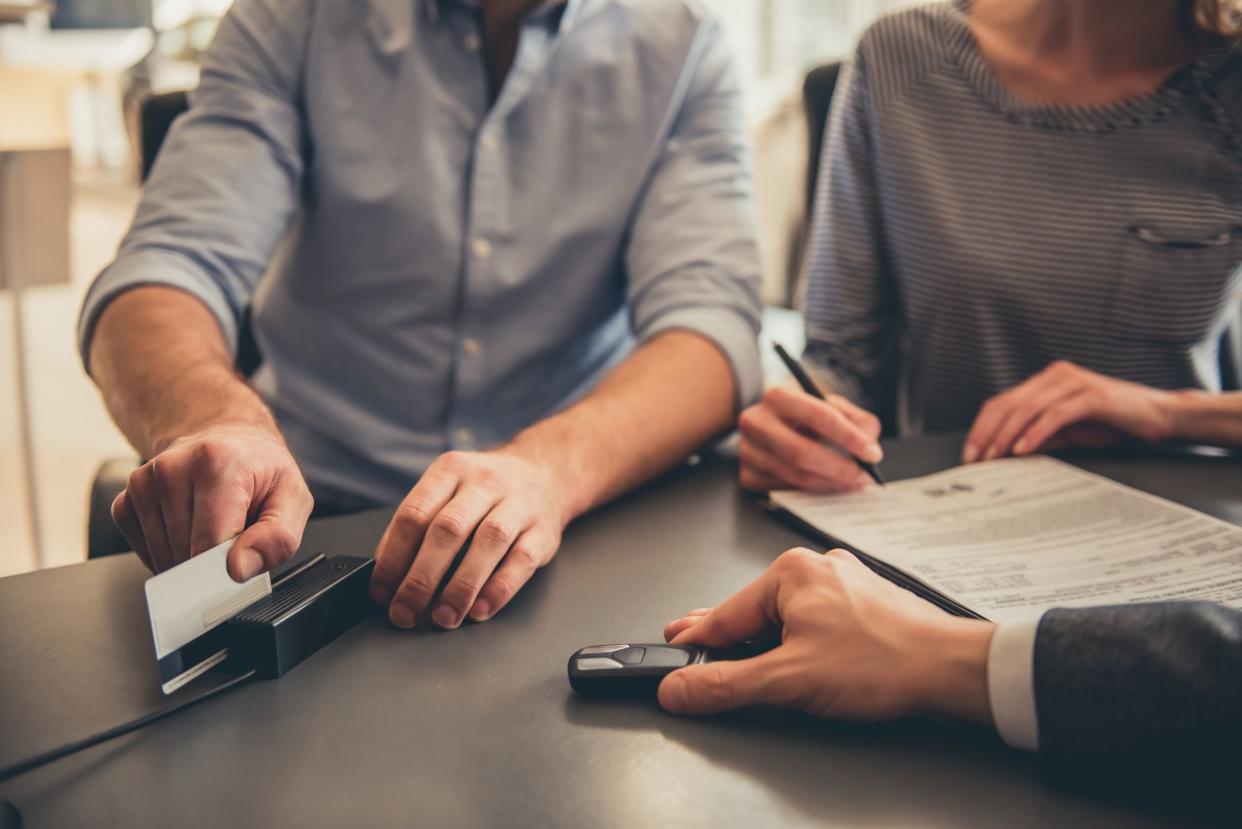 Visiting car dealership. Cropped image of beautiful couple paying with credit card for a new car