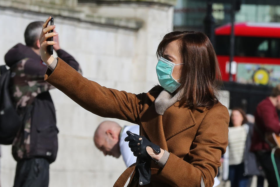 A woman wearing a face mask as a precaution against the spread of Coronavirus takes a selfie in central. (Photo by Steve Taylor / SOPA Images/Sipa USA)