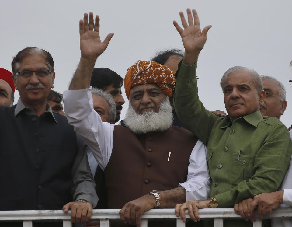 Radical cleric and leader of Islamist party 'Jamiat Ulema-e-Islam' Maulana Fazlur Rehman, center, waves to his supporters with opposition parties leader Shahbaz Sharif, right, and Nayar Bukhari during an anti-government march, in Islamabad, Pakistan, Friday, Nov. 1, 2019. Thousands of members of a radical Islamist party have camped out in Pakistan's capital, demanding the resignation of Prime Minister Imran Khan over economic hardships. (AP Photo/Anjum Naveed)