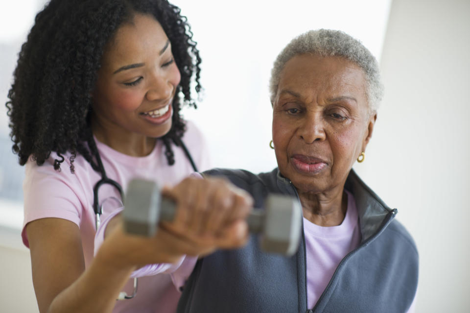 A physical therapist helps a patient lift a weight