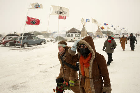 Campers walk through high winds during a blizzard inside of the Oceti Sakowin camp as "water protectors" continue to demonstrate against plans to pass the Dakota Access pipeline adjacent to the Standing Rock Indian Reservation, near Cannon Ball, North Dakota, U.S., December 6, 2016. REUTERS/Lucas Jackson