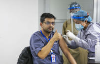 A Nepalese doctor shows thumbs up as he receives AstraZeneca/Oxford University vaccine, at Teaching Hospital in Kathmandu, Nepal, Wednesday, Jan. 27, 2021. Thousands of health workers lined up across Nepal to get the coronavirus vaccine Wednesday as the Himalayan nation began its campaign to get the population vaccinated within three months. Neighboring India gifted Nepal 1 million doses of the vaccine manufactured under license by the Serum Institute of India. (AP Photo/Niranjan Shrestha)