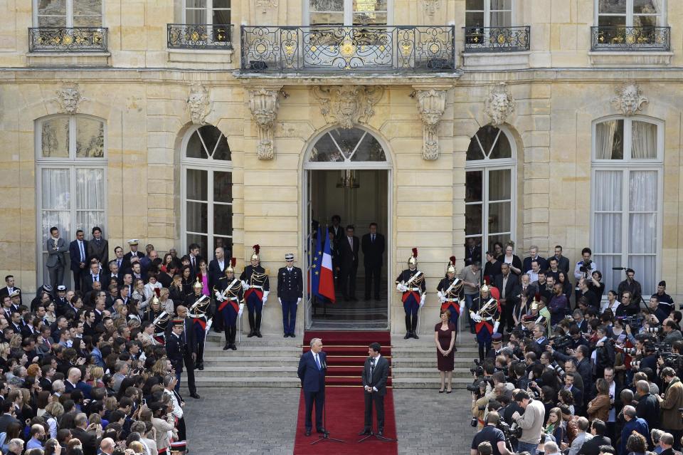 Outgoing French Prime Minister Jean-Marc Ayrault, left, looks at new French Prime Minister Manuel Valls, right on the carpet, after the takeover ceremony at the Prime Ministry in Paris, Tuesday, April 1, 2014. France's new prime minister is taking office after Socialist President Francois Hollande named Valls on Monday as prime minister. (AP Photo/Lionel Bonaventure, Pool)