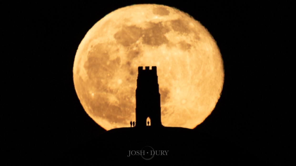  large full moon with a shadow in tower in front of it 