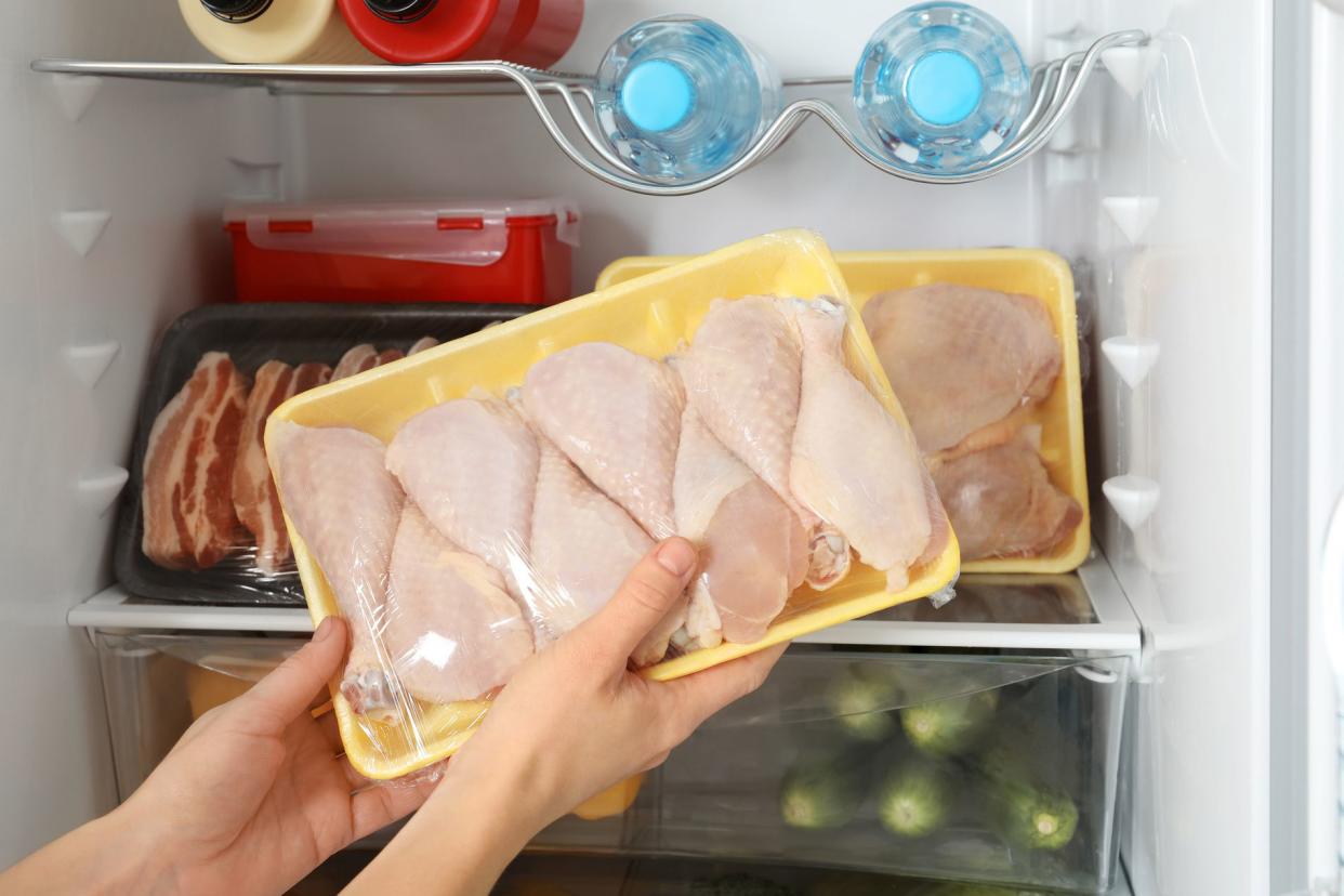 hands taking package of raw chicken drumsticks out of the fridge