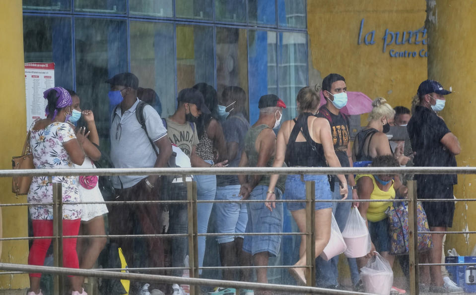 Con máscaras como precaución contra la propagación del nuevo coronavirus, la gente hace cola en la entrada de una tienda estatal de dólares en La Habana, Cuba, el viernes 11 de junio de 2021. (AP Foto/Ramon Espinosa)