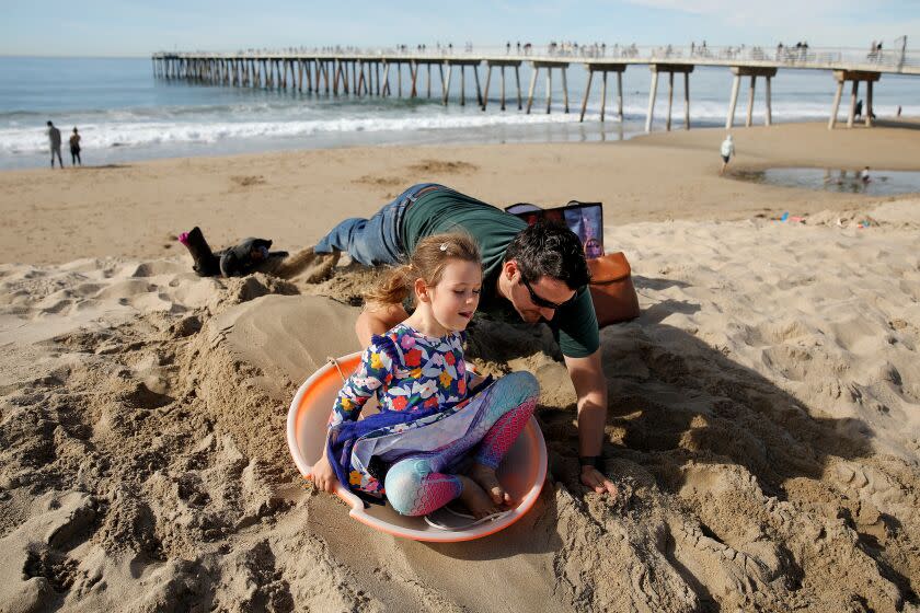HERMOSA BEACH, CA - DECEMBER 25: Alex Filipchik (cq), of Redondo Beach, pushes his dauther Veronica Filipchik, five, down a hill of sand on Sunday, Dec. 25, 2022 in Hermosa Beach, CA. What it's like to spend Christmas Day on the beach. Temperatures are supposed to hit low '80s on Sunday, while rest of country copes with winter storm. (Gary Coronado / Los Angeles Times)