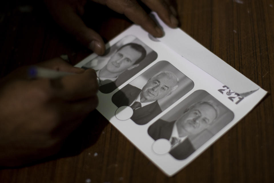 A man marks a ballot for Syria's President Bashar Assad during the Presidential elections, at a polling station in the town of Douma, near the Syrian capital Damascus, Syria, Wednesday, May 26, 2021. Syrians headed to polling stations early Wednesday to vote in the second presidential elections since the deadly conflict began in the Arab country. (AP Photo/Hassan Ammar)