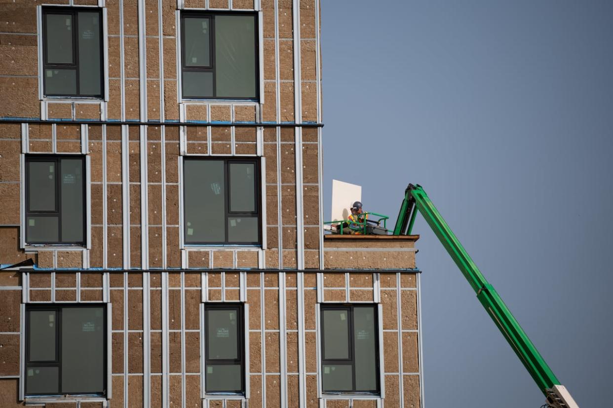 A construction worker uses an articulating boom lift to move a piece of construction equipment at the site of an affordable housing project in Ottawa on Sept. 28, 2023. (Spencer Colby/The Canadian Press - image credit)