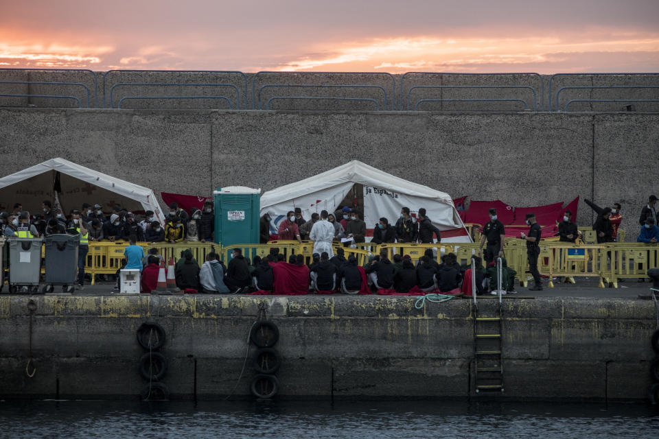 Migrants sit in Arguineguin port after their rescue in Gran Canaria island, Spain on Tuesday, Nov. 24, 2020. Spanish rescue services said Wednesday at least seven people died after a migrant boat carrying more than 30 people hit rocks close to a small port on the Canary Island of Lanzarote. Many of the rescued were taken to the Arguineguín dock on the southwestern coast of Gran Canaria island, where several thousand people of different origin are being kept, some in tents. (AP Photo/Javier Fergo)