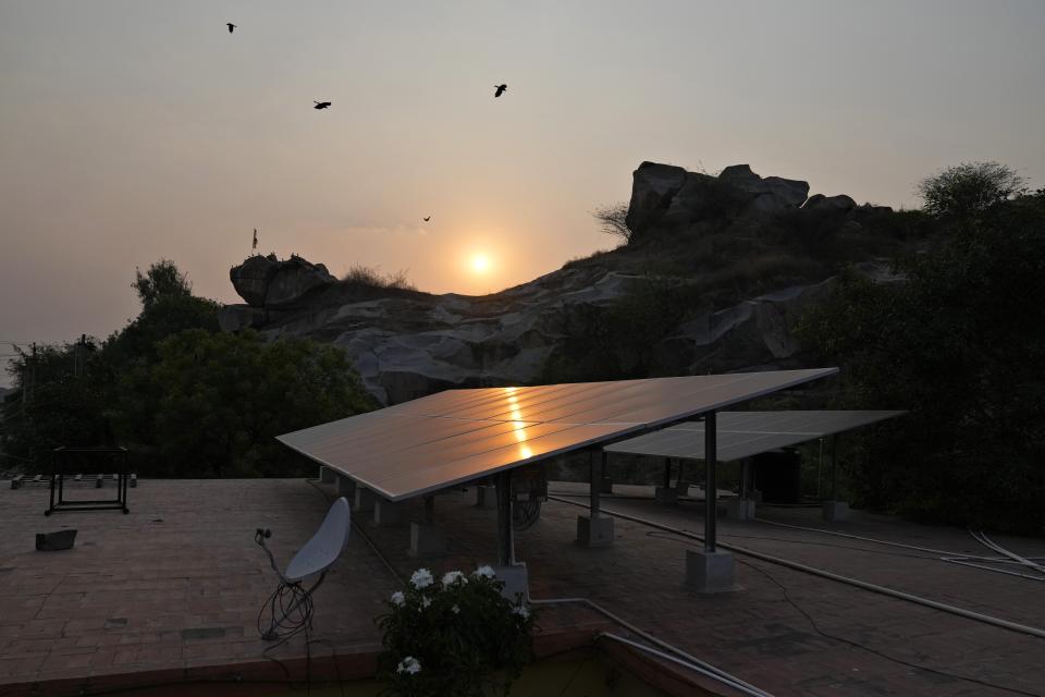 Birds fly at sunset over rooftop solar panels installed at a government maternity hospital to provide electricity, in Raichur, India, Wednesday, April 19, 2023. In semi-urban and rural regions of India and other developing countries with unreliable power grids, decentralized renewable energy — especially solar — is making all the difference in delivering modern health care. (AP Photo/Aijaz Rahi)