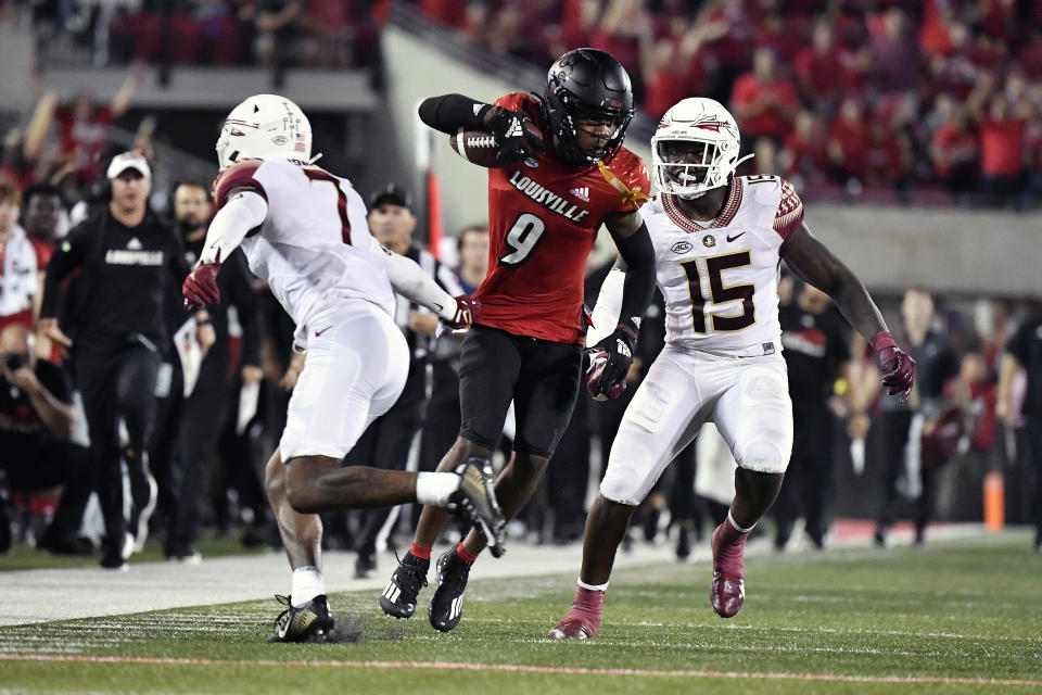 Louisville wide receiver Ahmari Huggins-Bruce (9) avoids the grasp of Florida State defensive back Jarrian Jones (7) as linebacker Tatum Bethune (15) continues the pursuit during the second half of an NCAA college football game in Louisville, Ky., Friday, Sept. 16, 2022. Florida State won 35-31. (AP Photo/Timothy D. Easley)