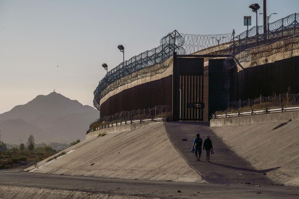 <span>Migrants walk along the border wall in El Paso, Texas, on 19 May 2022.</span><span>Photograph: Paul Ratje/AFP via Getty Images</span>