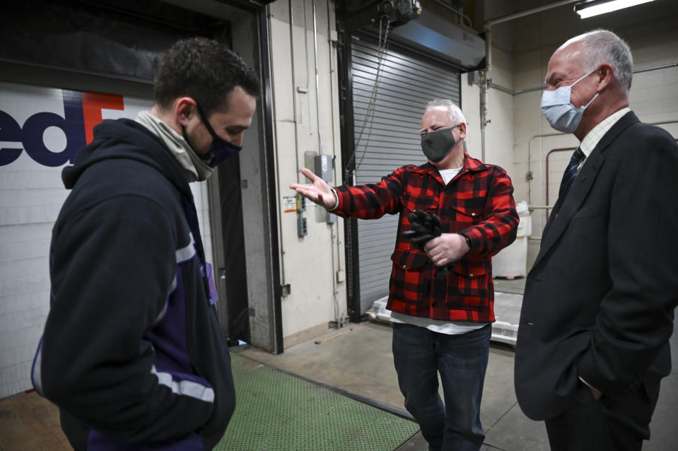 Minnesota Gov. Tim Walz, center, jokes with FedEx delivery driver Seth Warnecke before Warnecke delivered the first shipment of Pfizer-BioNTech COVID-19 vaccines to the Twin Cities at the Minneapolis VA Hospital Monday, Dec. 14, 2020. To their right is Patrick Kelly, director of the Minneapolis VA. (Aaron Lavinsky/Star Tribune via AP, Pool)