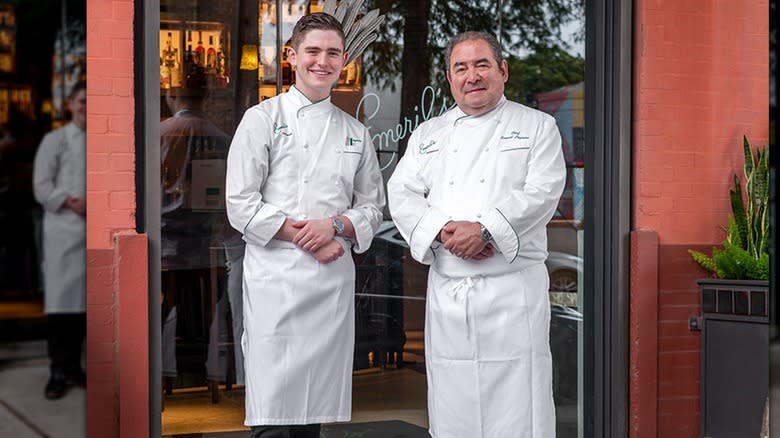 E.J. and Emeril Lagasse smiling in front of Emeril's restaurant