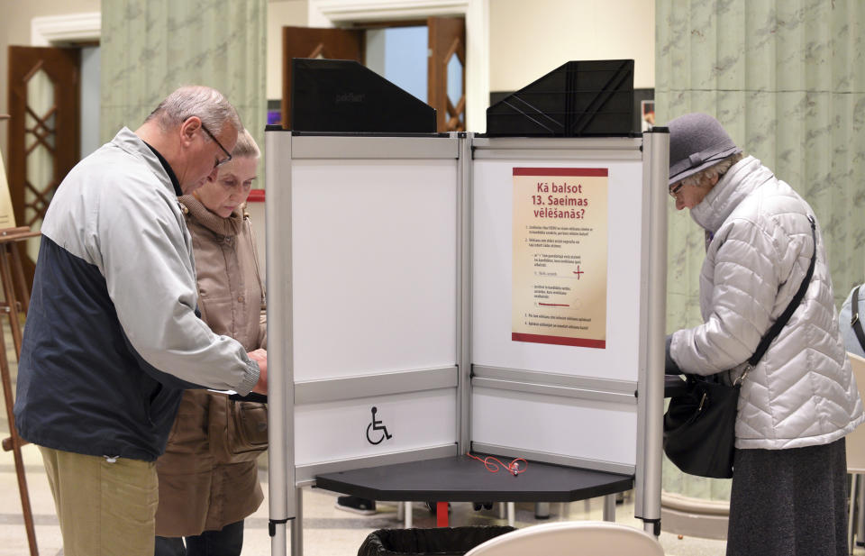 Latvians mark their ballots at a polling station in Riga, Latvia, Saturday, Oct. 6, 2018. Latvians were casting their ballots on Saturday in a parliamentary election in which a party catering to the Baltic nation's large ethnic-Russian minority is expected to win the most votes, but is seen to be struggling to find coalition partners. (AP Photo/Roman Koksarov)