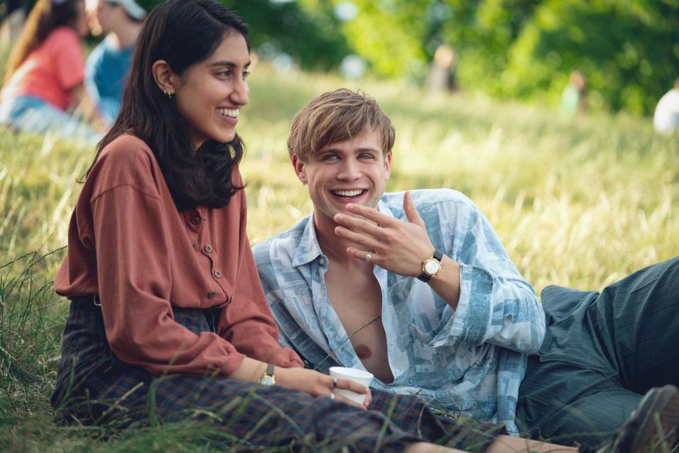 Ambika Mod, Leo Woodall sitting in the grass together in scene from Netflix's "One Day"