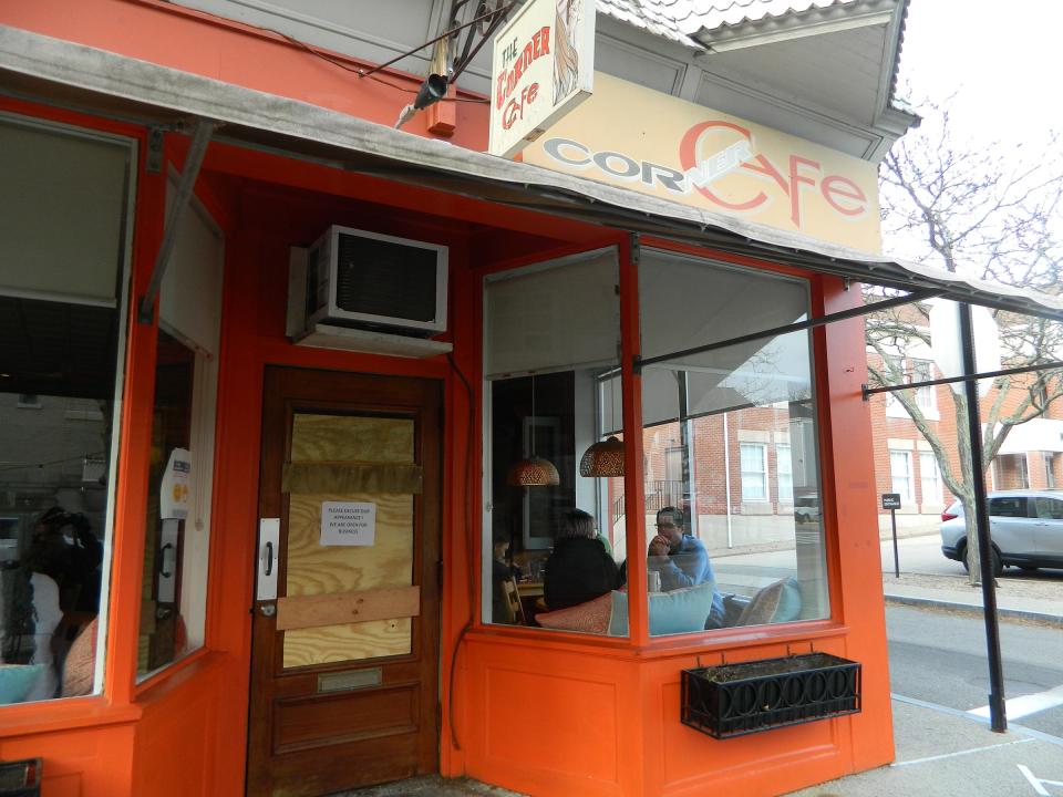 A sign at the entrance to Corner Cafe alerts customers the business is open after a window was smashed early Sunday.