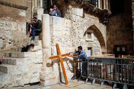 A man touches a wooden cross, at the entrance to the Church of the Holy Sepulchre in Jerusalem's Old City, February 25, 2018. REUTERS/Amir Cohen