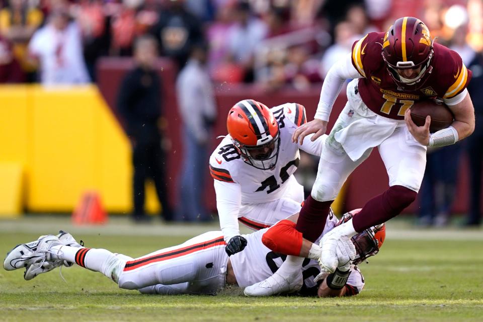 Washington Commanders quarterback Carson Wentz (11) is tacked by Cleveland Browns defensive end Chase Winovich (69) and Cleveland Browns linebacker Jermaine Carter (40) during the second half of an NFL football game, Sunday, Jan. 1, 2023, in Landover, Md. (AP Photo/Patrick Semansky)