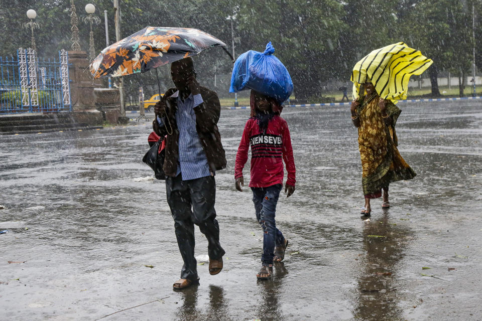 Indians walk in the rain in Kolkata, India, Saturday, Nov. 9, 2019. Authorities in nearby Bangladesh put more than 50,000 volunteers on standby and readied about 5000 shelters as a strong cyclone in the Bay of Bengal is expected to hit the low-lying nation's vast southwestern and southern coast on Saturday evening. (AP Photo/Bikas Das)