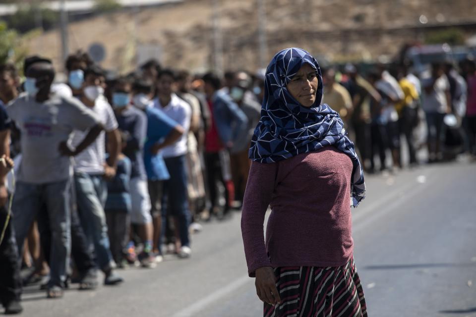 Migrants wait for food distribution near Mytilene town, on the northeastern island of Lesbos, Greece, Friday, Sept. 11, 2020. Thousands of protesting refugees and migrants left homeless on the Greek island of Lesbos after fires destroyed the notoriously overcrowded Moria camp have gathered on a road leading to the island's main town, demanding to be allowed to leave. (AP Photo/Petros Giannakouris)