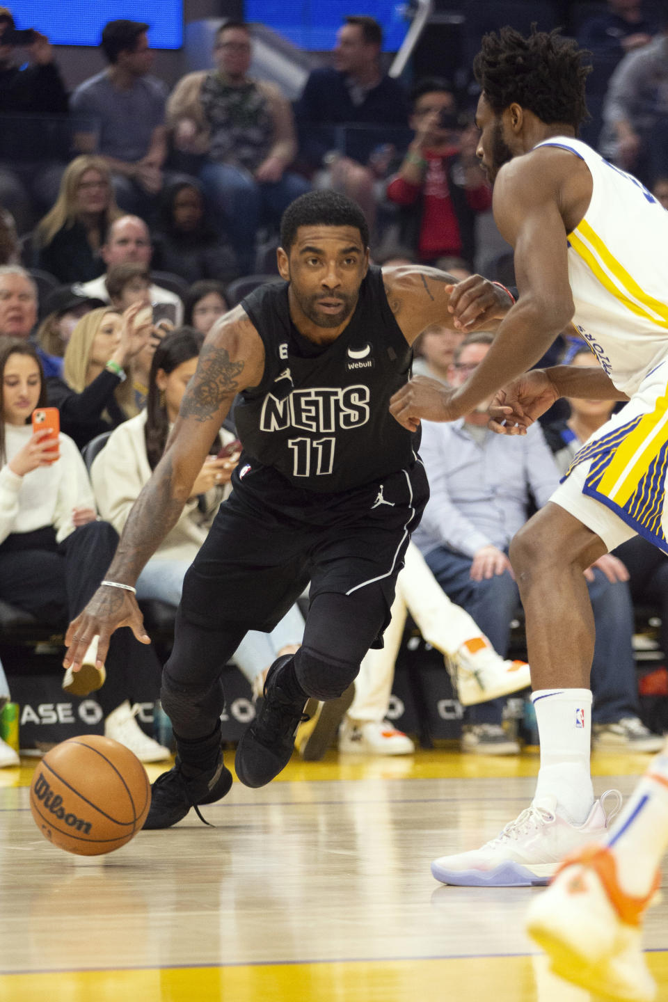 Brooklyn Nets guard Kyrie Irving (11) drives past Golden State Warriors forward Andrew Wiggins during the first quarter of an NBA basketball game, Sunday, Jan. 22, 2023, in San Francisco. (AP Photo/D. Ross Cameron)
