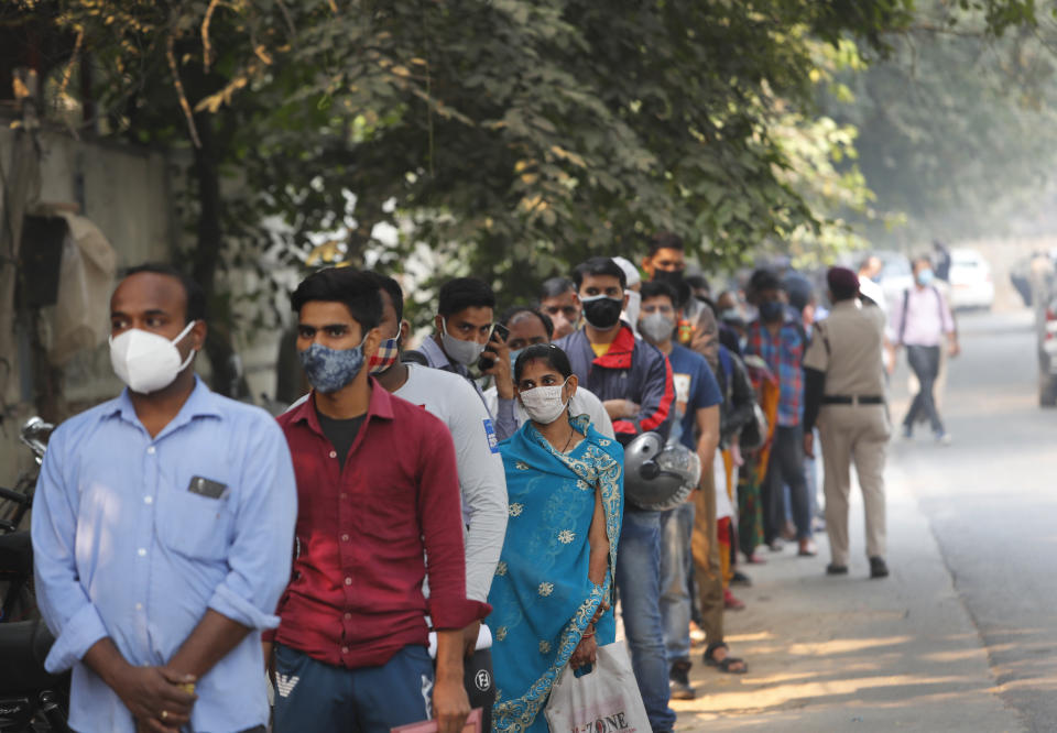 FILE - In this Nov. 6, 2020, file photo, people queue to get tested for COVID-19 as a thick quilt of smog lingers over New Delhi, India. India is grappling with two public health emergencies: critically polluted air and the pandemic. Nowhere is this dual threat more pronounced than in the Indian capital New Delhi, where the spike in winter pollution levels has coincided with a surge of COVID-19 cases. (AP Photo/Manish Swarup, File)