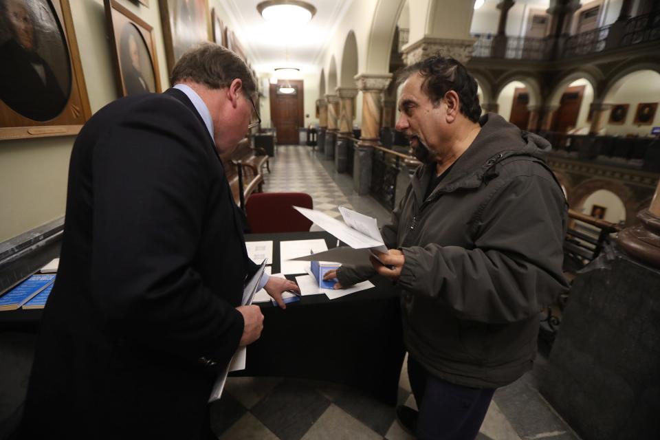 Scott Dean, consumer program specialist with the New York State Dept. of Public Service, gives Abdul Mohammed of Henrietta, information about his rights as a natural gas or electric customer and gives him the sheet to lodge a complaint during a public forum about complaints about RG&E and NYSEG held at Rochester City Hall. 