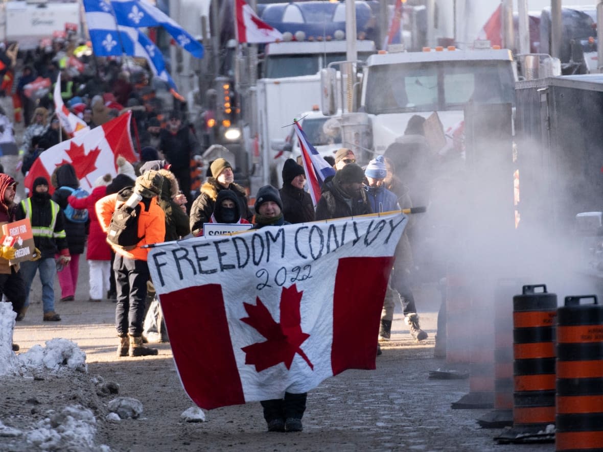 Protesters participating in a cross-country truck convoy protesting measures taken by authorities to curb the spread of COVID-19 and vaccine mandates walk near Parliament Hill in Ottawa on Saturday, Jan. 29, 2022.  (Adrian Wyld/Canadian Press - image credit)