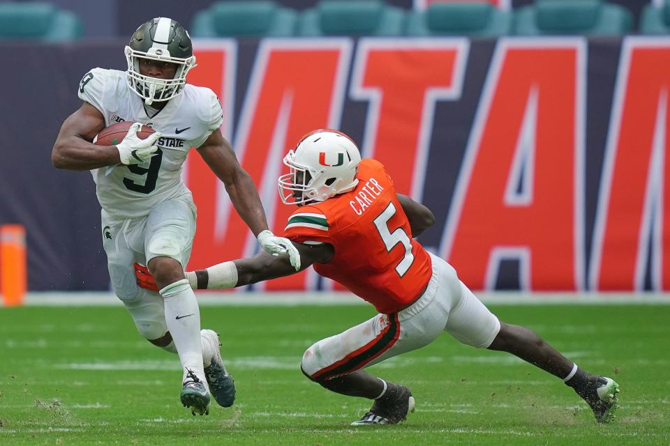 Michigan State Spartans running back Kenneth Walker III runs the ball past Miami Hurricanes safety Amari Carter during the second half in Miami Gardens, Fla. on Sept. 18, 2021.