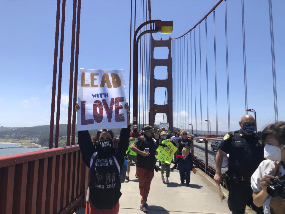Dozens of people gathered by the Golden Gate Bridge Welcome Center in San Francisco Saturday, June 6, 2020, and march across the famous span in support of the Black Lives Matter movement. People are protesting the death of George Floyd, who died after he was restrained by Minneapolis police on May 25 in Minnesota. (AP Photo/Jeff Chiu)