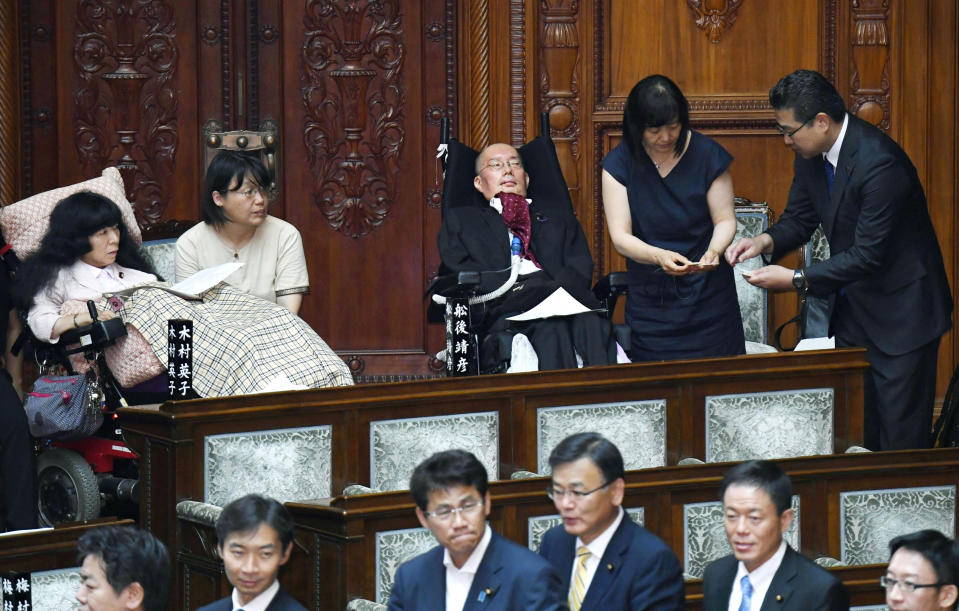 Two newly-elected lawmakers, Yasuhiko Funago, third from right, and Eiko Kimura, left, in wheelchairs are helped to vote during an extraordinary session of the parliament's upper house in Tokyo Thursday, Aug. 1, 2019. Japan’s parliament convened after elections and a minor renovation at the upper house. Funago, who has Amyotrophic Lateral Sclerosis, a progressive neurological disease known as ALS, and Kimura who has cerebral palsy, won the July 21 elections at the less-powerful of the two chambers, representing an opposition group. (Muneyuki Tomari/Kyodo News via AP)