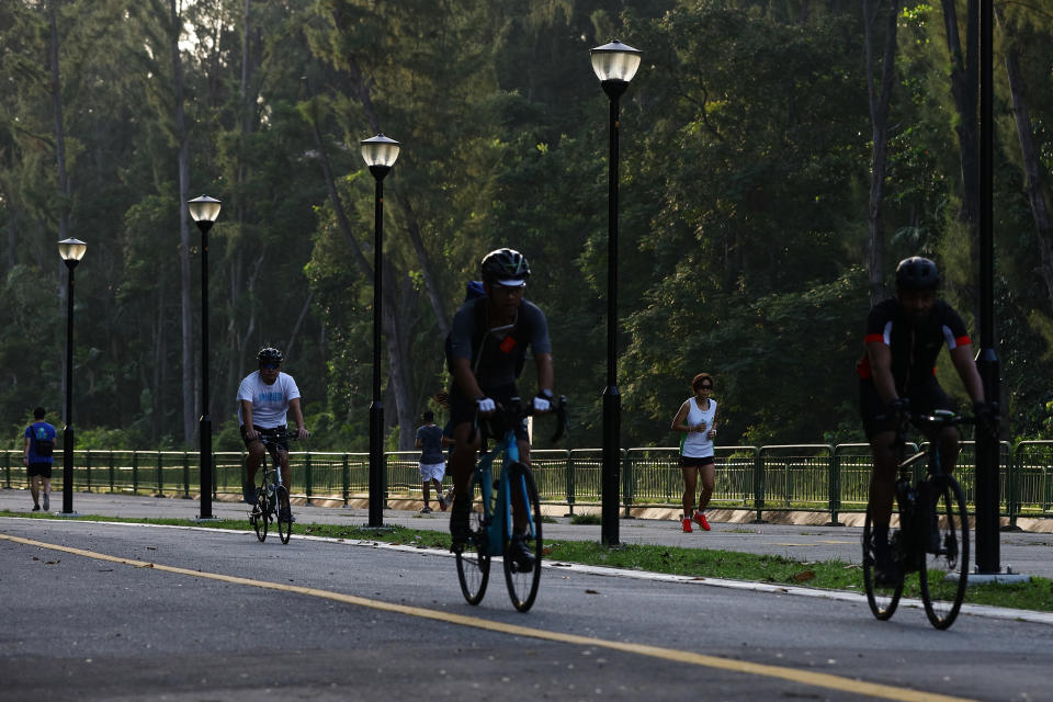 SINGAPORE - APRIL 10:  People are seen jogging and cycling at a park on April 10, 2020 in Singapore. The Singapore government announced it will close open-air stadiums after people continued to disregard social-distancing rules by exercising in groups. The authority warned it will further tighten access to parks for non-compliance and urged park goers not to exercise, jog or cycle in groups to help prevent more coronavirus (COVID-19) clusters from emerging in the community.  (Photo by Suhaimi Abdullah/Getty Images)