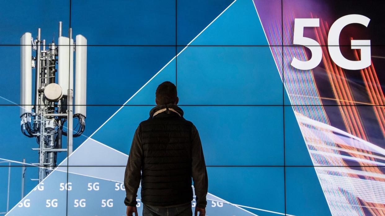 Ein Mann steht im Gebäude der Bundesnetzagentur vor einer Leinwand mit der Aufschrift «5G». Die Bundesnetzagentur versteigert 41 Frequenzblöcke an verschiedene Anbieter. Foto: Boris Roessler