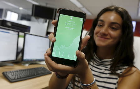 Madison Lucas, an employee of U.S.-based technology company Acorns, demonstrates their smartphone-based app at the organization's Sydney headquarters in Australia, April 19, 2016. REUTERS/Jason Reed