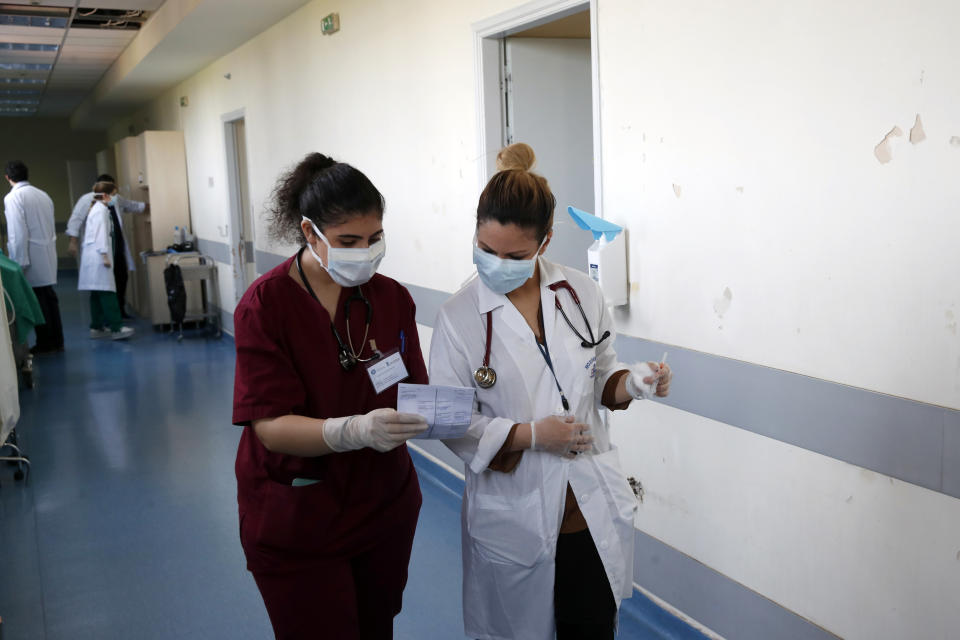 In this photo taken on Wednesday, May 6, 2020, medical student Adamantia Papamichail, left, shows notes to internal medicine Katerina Bakiri at the Pathological Clinic of Sotiria Hospital in Athens. Greece's main hospital for the treatment of COVID-19 is also the focus of a hands-on training program for dozens of medical students who volunteered to relieve hard-pressed doctors from their simpler duties while gaining a close peek at the front lines of a struggle unmatched in modern medical history. (AP Photo/Thanassis Stavrakis)