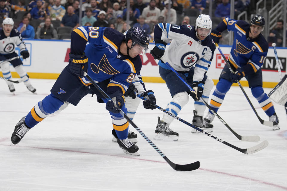 St. Louis Blues' Brandon Saad (20) handles the puck as Winnipeg Jets' Adam Lowry (17) defends during the second period of an NHL hockey game Tuesday, Nov. 7, 2023, in St. Louis. (AP Photo/Jeff Roberson)