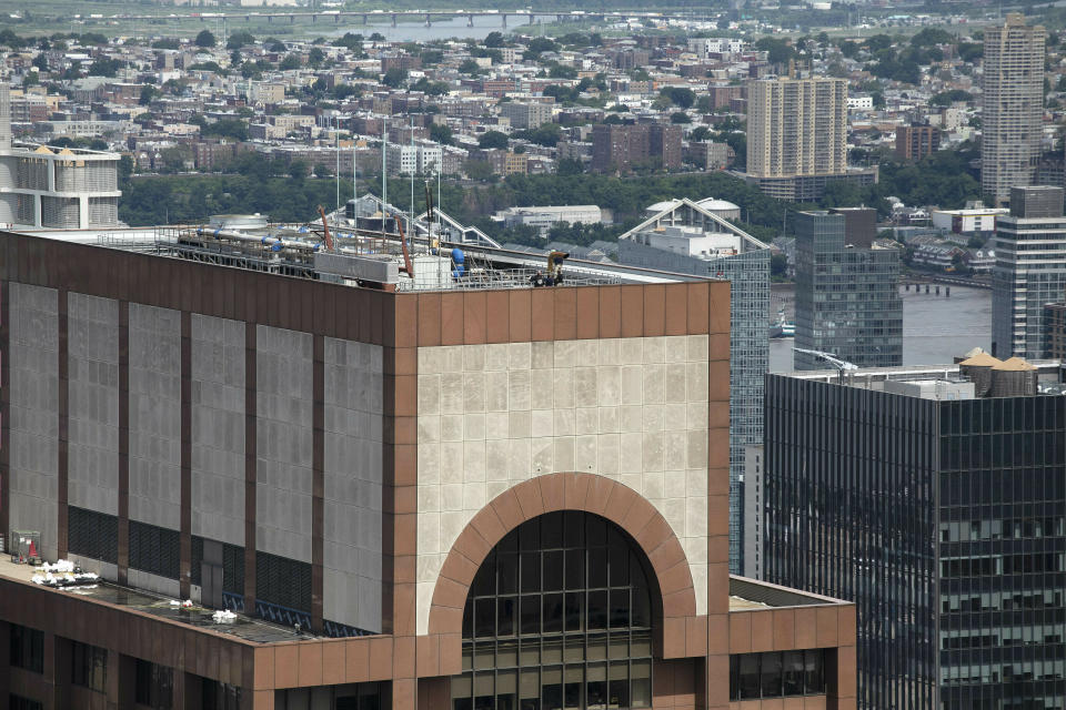 Law enforcement personnel work on the roof of the AXA Equitable building, Tuesday, June 11, 2019 in New York. A helicopter crashed Monday on the roof of the rain-shrouded Manhattan skyscraper, killing the pilot, Tim McCormack, of Clinton Corners, N.Y. (AP Photo/Mark Lennihan)