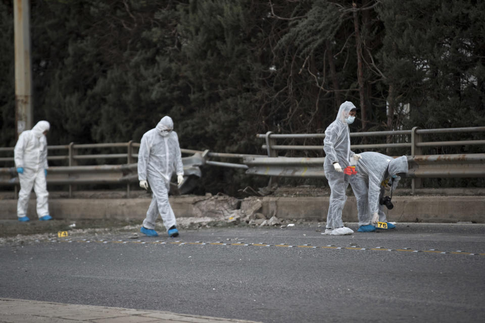 Greek forensic experts search at the scene after a powerful bomb exploded outside private Greek television station Skai, in Faliro, Athens, Monday, Dec, 17, 2018. Police said the blast occurred outside the broadcasters' headquarters near Athens after telephoned warnings prompted authorities to evacuate the building, causing extensive damage but no injuries. (AP Photo/Petros Giannakouris)