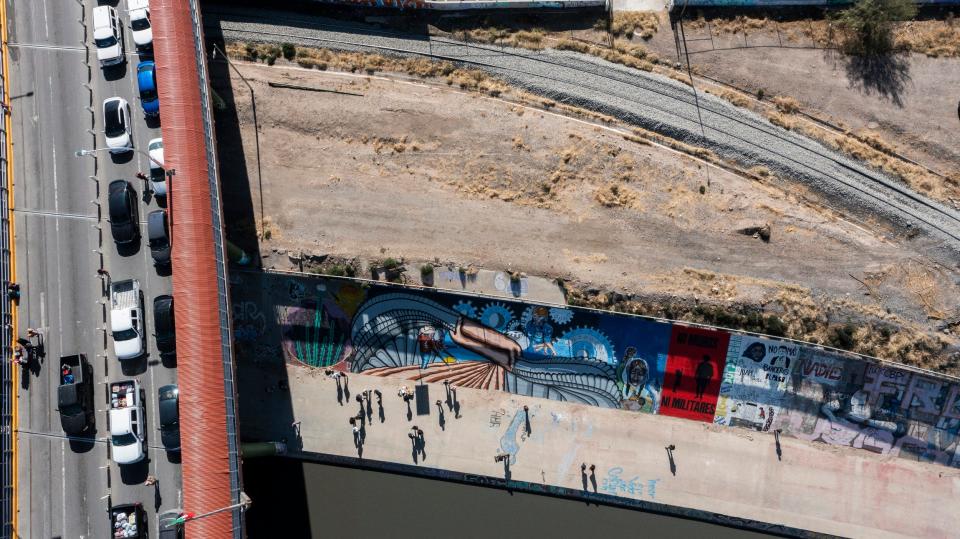 A mural depicting a 'bracero' farmworker and a maquiladora worker depict the migrant experience in the El Paso/Ciudad Juarez binational community. The mural titled 'Under the Bridge/Bajo el Puente' is the creation of Jorge Perez Mendoza, an artist from Ciudad Juarez. At far left is the El Paso del Norte international bridge connecting both communities.